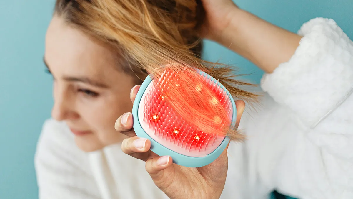 A woman using FLIP™ play advanced LED light hairbrush
